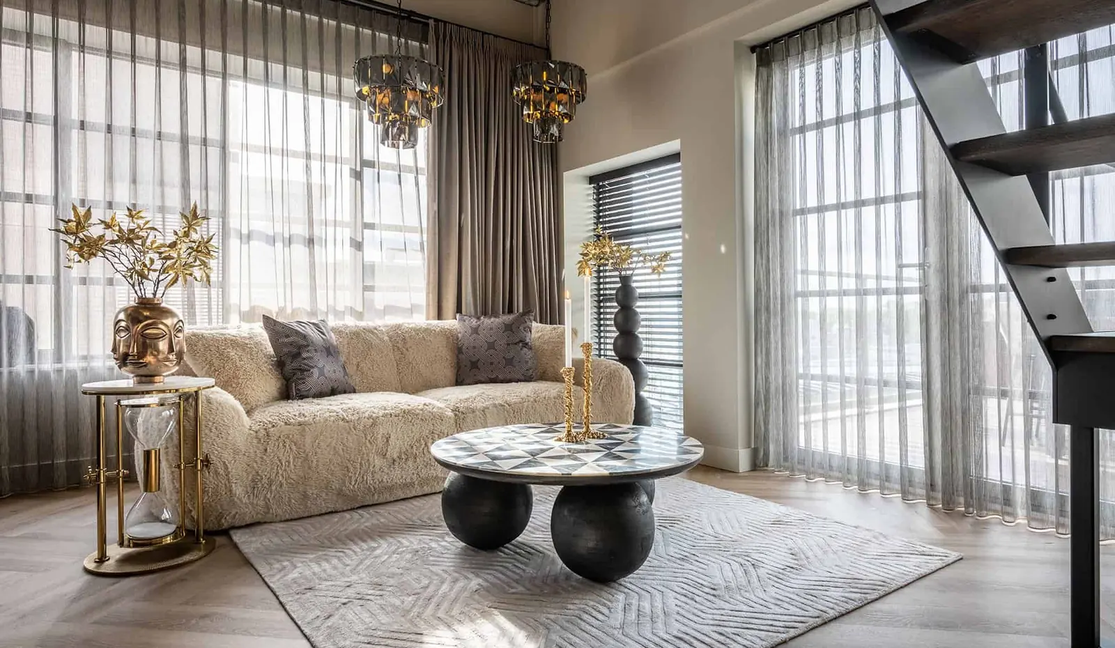 Richmond Interiors svetainės interjeras su šviesia sofa, marmuro efekto staliuku ir žalvario akcentais